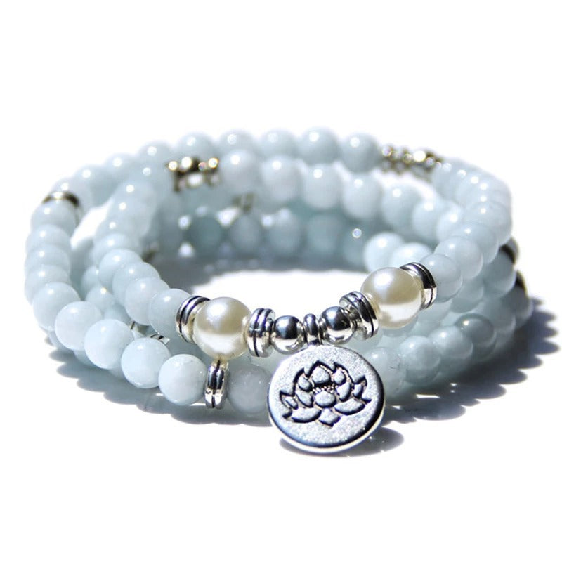Set of light blue beaded bracelets with pearl and silver lotus charm on a white background